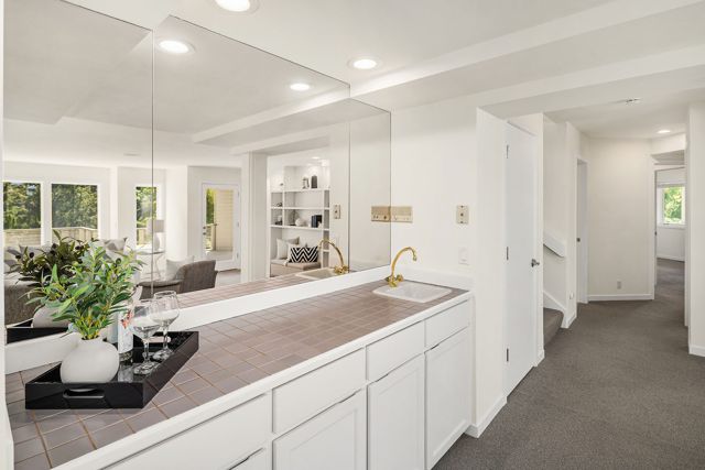 Wet bar with white cabinets and tile counter
